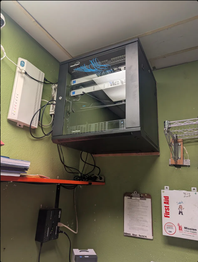 After: clean wall-mounted NavePoint network rack with managed switch and tidy cabling at Fibber Magee's Irish Pub